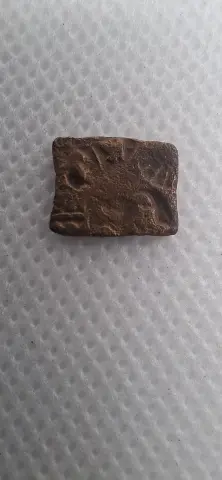 Lateral da moeda TH-N-0122 — Índia Antiga, pequena peça de cobre retangular com possíveis marcas de punção